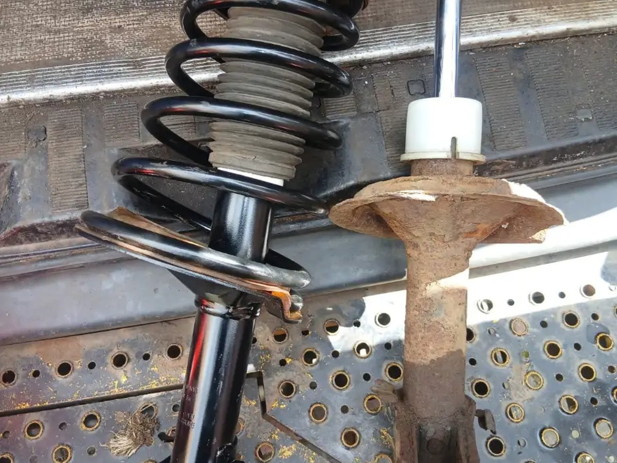 A new coil spring and strut assembly beside the corroded original removed from the vehicle